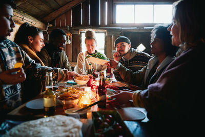 Male and female friends talking while having meal in cottage during weekend