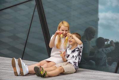 Happy blond woman and little boy sitting on terrace and eating sweets. mother and son 