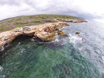 Rock formation in sea against sky