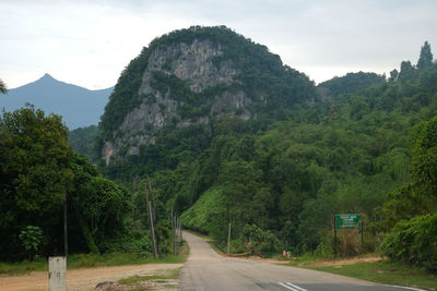 Road amidst trees and mountains against sky