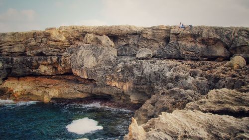 Rock formations by sea against sky