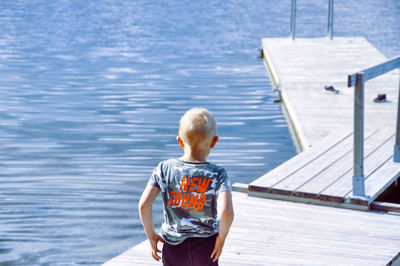 Rear view of man standing on pier over sea