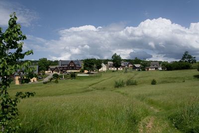 Scenic view of field by buildings against sky