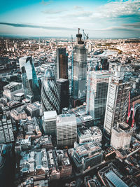 Aerial view of modern buildings in city against cloudy sky