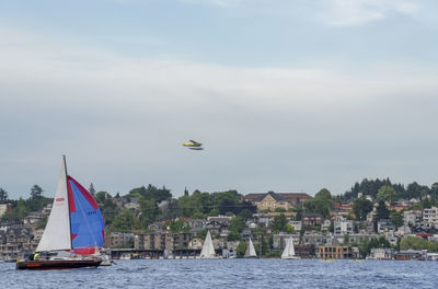 Sailboats in sea against buildings in city