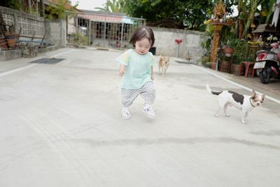 Cute baby girl stamping foot on footpath with dogs in background