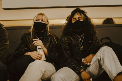 Female friends sitting at subway during pandemic