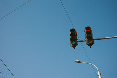 Low angle view of road signal against clear blue sky during sunny day