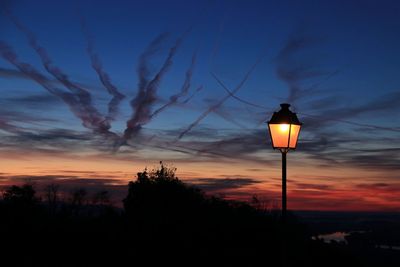 Low angle view of illuminated street light against sky at sunset