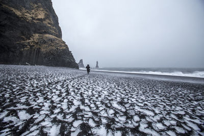 Man standing on beach against sky during winter