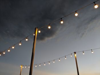 Low angle view of hanging lightbulbs at night