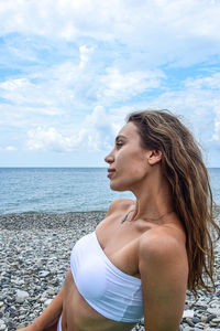 Young woman looking at sea shore against sky