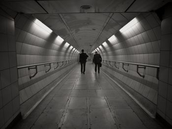 Rear view of people walking in illuminated tunnel