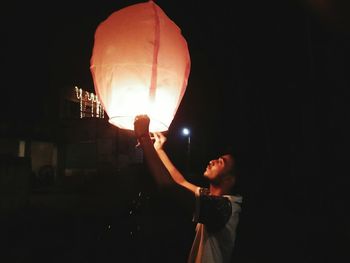 Man standing in illuminated lantern against black sky