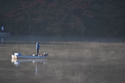 Man standing on boat in lake