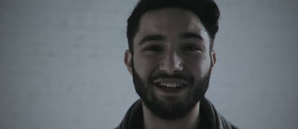 Close-up portrait of happy bearded man against wall