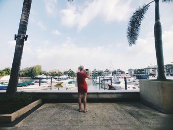 Rear view of woman photographing with mobile phone while standing by sea against sky