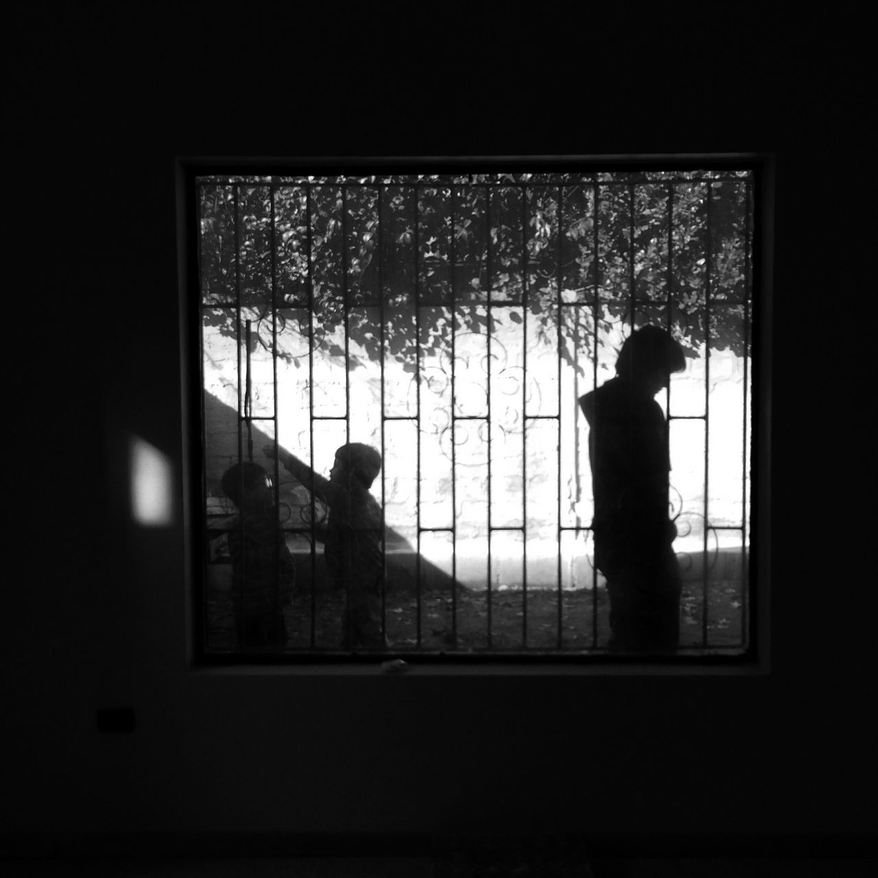 window, silhouette, indoors, architecture, built structure, glass - material, standing, transparent, men, lifestyles, dark, looking through window, rear view, building exterior, leisure activity, house, full length