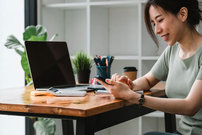 Woman using mobile phone while sitting on table