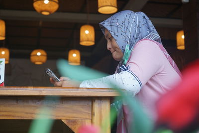 A woman is sitting in a restaurant looking at a cell phone