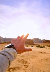 Close-up of hand holding sand in desert against sky