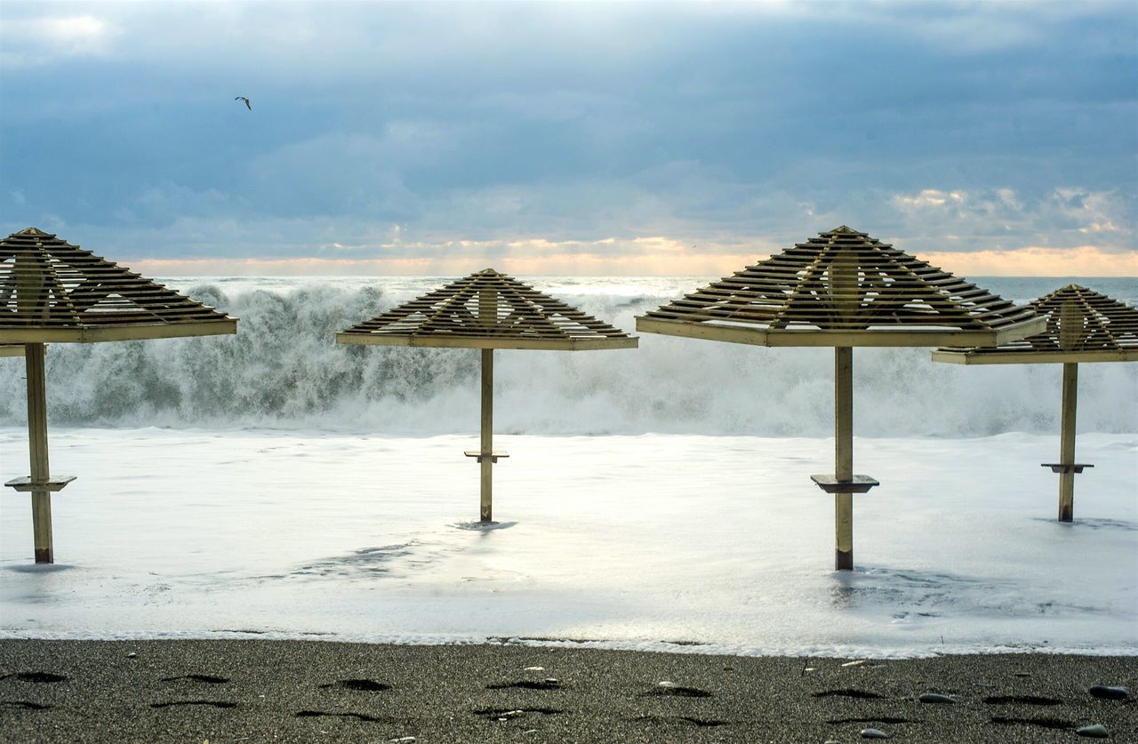 beach, parasol, beach umbrella, cloud - sky, water, protection, rain, outdoors, sea, nature, no people, sky, day, architecture