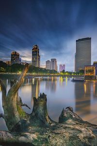 River by buildings against sky in city at dusk