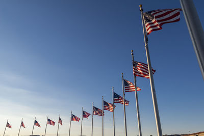 Low angle view of american flags against blue sky