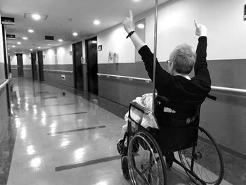 Rear view of woman on wheelchair in corridor