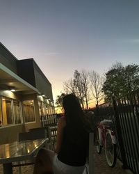 Woman sitting on seat against sky during sunset