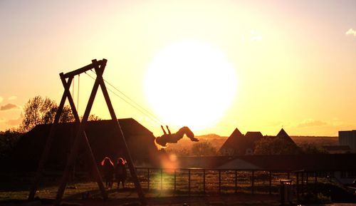 Silhouette man on playground against sky during sunset