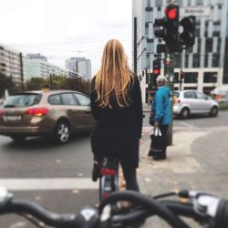 Rear view of woman with bicycle on street