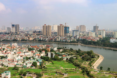 Cityscape by river against sky