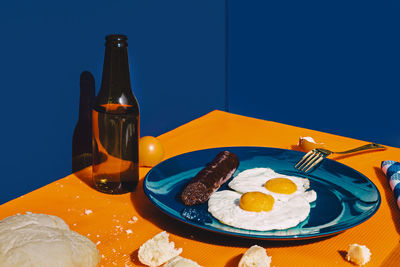 Bottle of beer and plate with fried eggs and chorizo