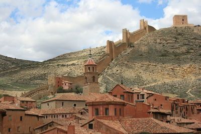 Buildings in town against cloudy sky