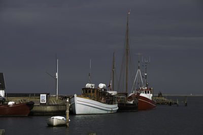 Sailboats moored on sea against sky