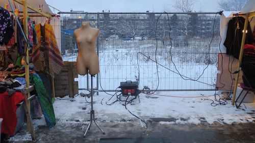 View of a snow-covered dress form with electrical cables on a public flea market on a nice day