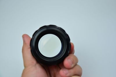 Close-up of hand holding camera over white background