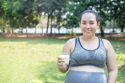 Portrait of pregnant woman smiling while having drink at park