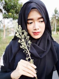 Portrait of young woman holding plant