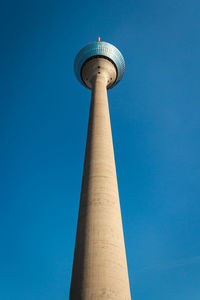 Low angle view of communications tower against blue sky