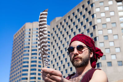 Portrait of man wearing hat against building in city