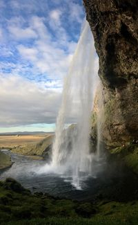 Scenic view of waterfall against sky