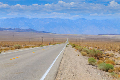 Road leading towards mountains against sky