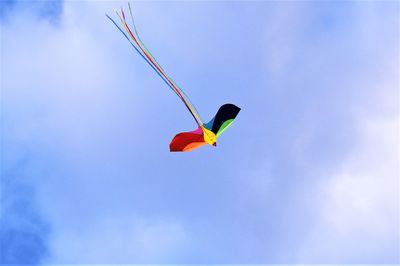 Low angle view of red kite flying against blue sky