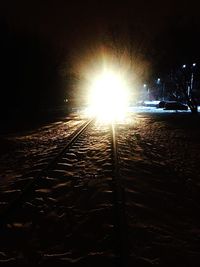 Illuminated railroad tracks against sky at night