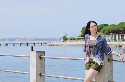 Portrait of smiling young woman standing against lake