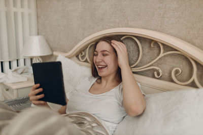 Young woman using mobile phone while sitting on sofa at home