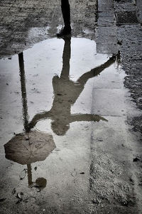 Low section of person standing on wet footpath