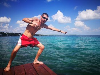 Full length of shirtless man in sea against sky